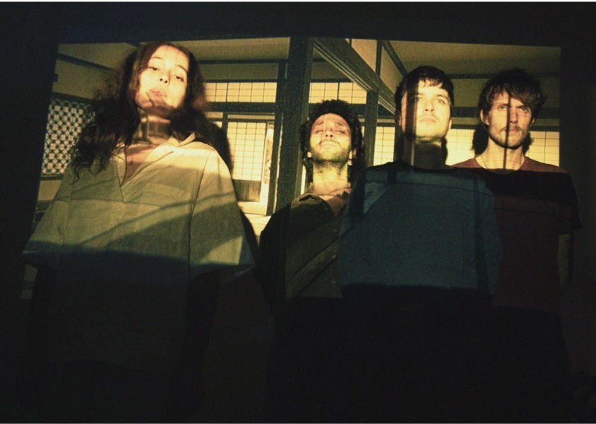 Azamiah band members looking into the camera with a room being projected onto their faces.x